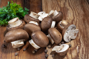 Royal mushrooms champignon whole and cut into pieces, scattered peppers, close-up on a wooden background, rustic style