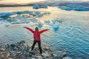 Sporty woman near Ice Glacier Lagoon Jokulsarlon over sunset. Icebergs drifting towards the sea. Great tourist spot of Iceland. © Kotangens
