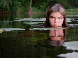 mermaid girl in the water among water lilies at sunset