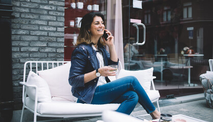 Cheerful woman speaking on phone in street cafe