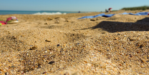 Close up of sand on the beach. With blurred ocean background and visible sea and sky. Concept for travel, holidays and vacations. With copy space or for product presentation.