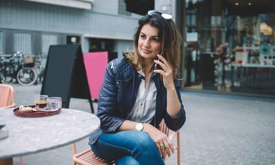 Confident female speaking on smartphone in sidewalk cafe