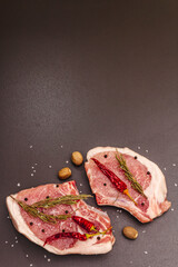 Raw pork steaks on trendy black stone concrete background