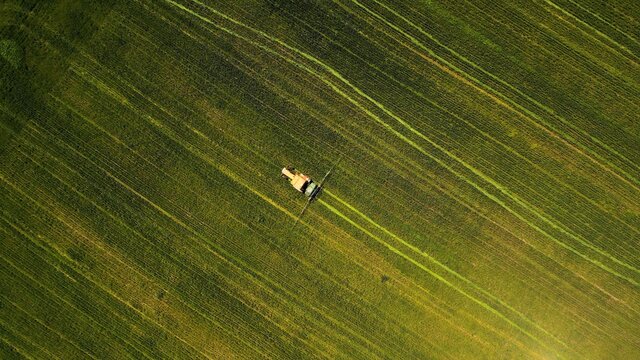 Overhead Shot Of A Tractor Treating An Agricultural Field During Daylight