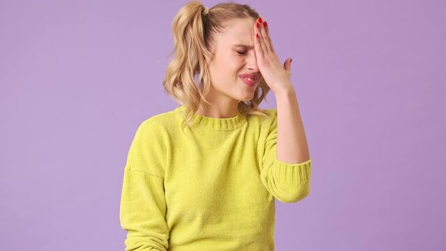A wonderful girl in a yellow sweater remembered that she forgot to do an urgent task in the isolated studio on a purple background