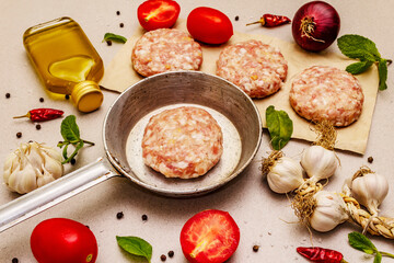 Raw cutlets, fresh vegetables, spices, olive oil. Vintage pan, picnic or barbecue cooking concept