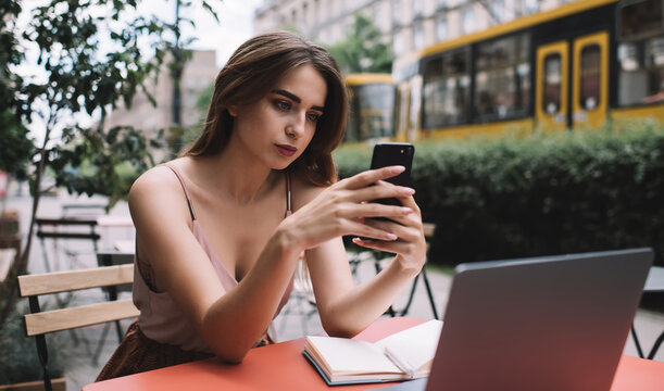 Focused woman surfing smartphone in street cafe