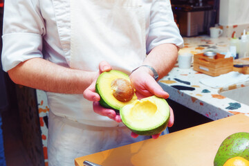 Chef is showing an avocado cut in two pieces, toned