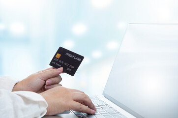 Selective focus at overweight woman's hand holding credit card mock up and using laptop computer in office room
