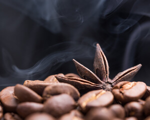 Aroma roasted coffee beans and star anis with smoke rising over dark background