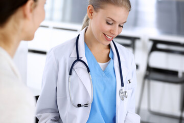 Doctor and patient during consultation. Physician at work filling up medication history record while sitting in emergency hospital, portrait shoot. Medicine and health care concept