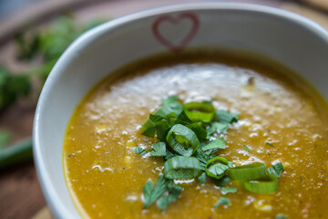 Sopa com pedaços de milho e cebolinha por cima.