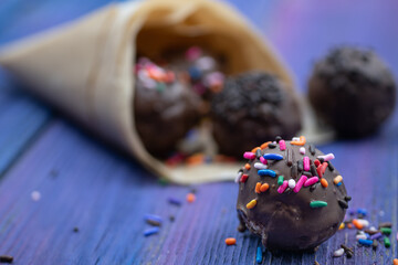 Chocolate donut holes with sprinkles in paper cone, copy space