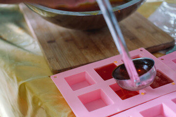 hand pouring soap mixture on plastic form