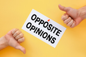 Male hands show signs of approval or disapproval. Postcard with the inscription Opposite Opinions on a yellow background