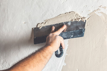 Hand with putty knife repair wall, Hand with a spatula, spatula with spackle paste structure,...