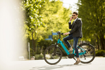 Young businessman on the ebike using mobile phone