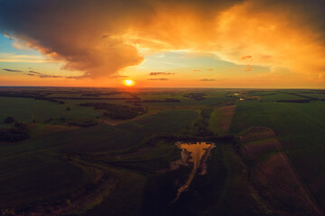Aerial view on the field during sunset. Agricultural landscape from drone.