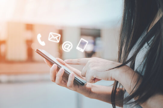 Close-up image of woman hands using smartphone with icon telephone email mobile phone and address. Contact us connection and e-mail marketing concept