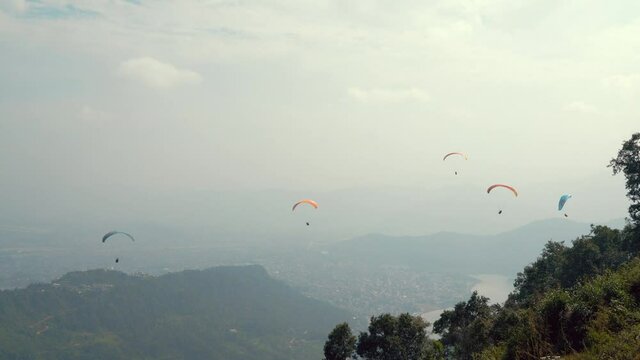 4K aerial view to Pokhara in Nepal - the third biggest nepalese city with floating over the valley and Phewa Lake paragliders. Paragliding is very popular entertainment for tourists here.