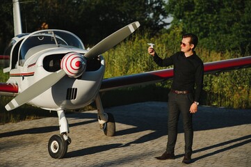 Fototapeta premium Pensive attrative young man pilot standing near small aircraft