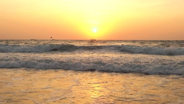 The beautiful fiery sunset over the waves of Goa, India - wide