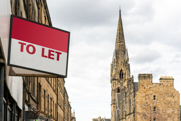 Estate agency 'To Let' sign board with typical British buildings in the background