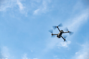 The flying soaring drone in the sky, the blue sky with white clouds, sunny weather, Turning propellers, nobody