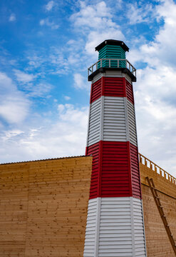 Wooden sea lighthouse on a background of blue sky on a sunny day. Vertical picture.