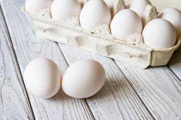 Close-up of fresh white organic chicken eggs in the paper tray on light wooden background