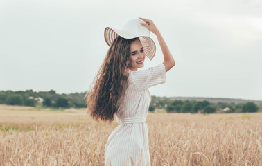 
Girl in a wheat field runs with a hat