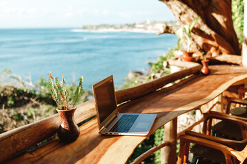 Open laptop with black screen  on wooden table work space outdoors with amazing view on the ocean....