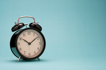 closeup of beautiful black alarm clock on green background wit copy space.