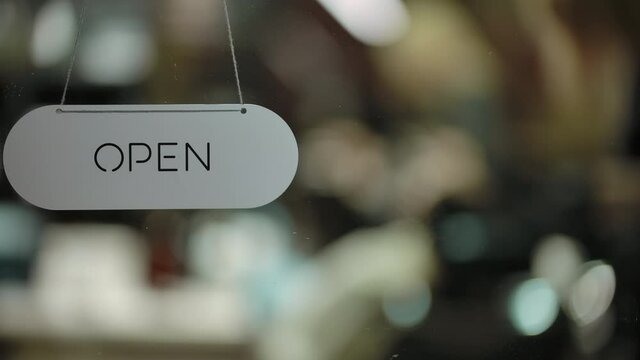 Refocusing from barber with client to open nameplate. Haircut specialists in mall business, modern barbershop, making their job. We are open for each customer now, and ready to make haircut.