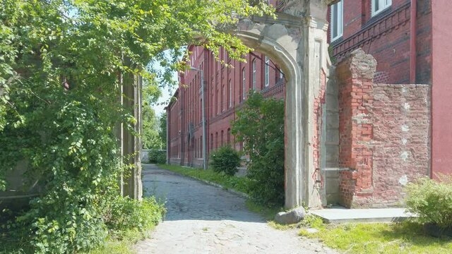 Arched portal gate of old historical residential building - landmark of german prussian architecture in Kaliningrad, Russia (formerly Koenigsberg) at sunny spring day. Static shot rendered in 4K