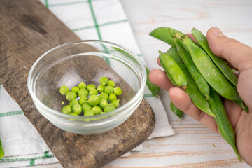 raw green pea in a glass bowl on wooden board