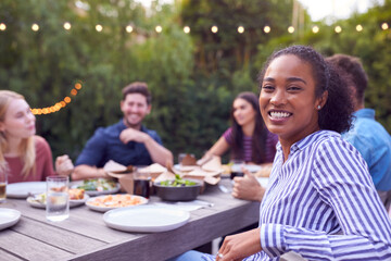 Portrait Of Multi-Cultural Friends  At Home Sitting At Table Enjoying Summer Garden Party