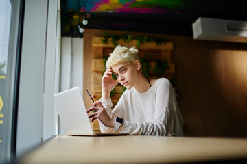 Concentrated young female freelancer concentrated on finding solutions for project earning money on...