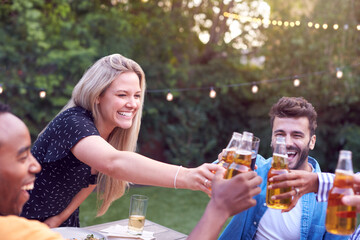 Friends Making Toast With Alcohol In Garden At Home Enjoying Summer Garden Party