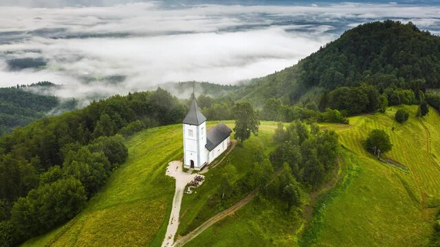 Jamnik, Slovenia - Aerial time-lapse (hyperlapse) footage of drone flying over St Primoz church on a foggy summer morning in the municipality of Kranj in the Upper Carniola region of Slovenia