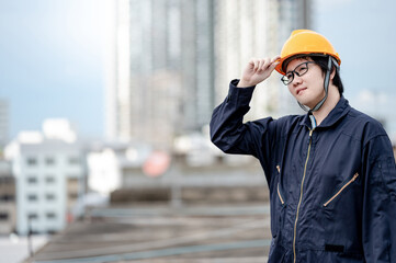 Asian maintenance worker man wearing protective suit and safety helmet working at construction site. Civil engineering, Architecture builder and building service concepts