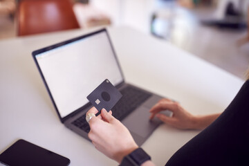 Close Up Of Woman In Kitchen Making Online Credit Card Purchase On Laptop