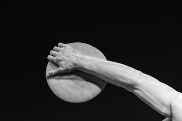 Black and white photo showing in detail hand of ancient roman statue holding a discus