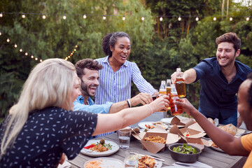 Multi-Cultural Friends At Home Around Table Making A Toast As They Enjoy Food At Summer Garden Party