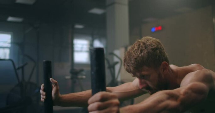 a tenacious single-minded male athlete pushes a heavy sled in the gym. exercise with a heavy weight for endurance