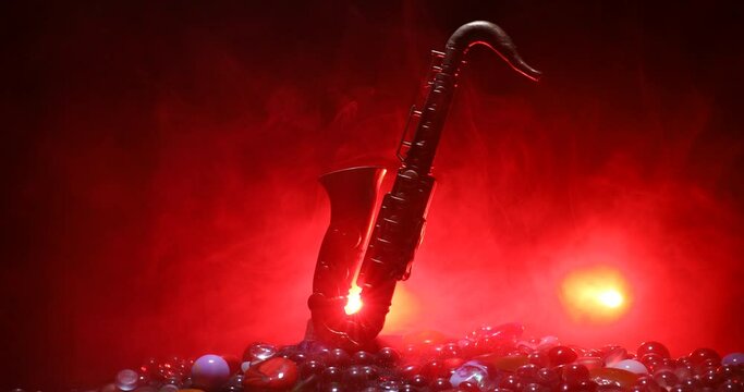 Music concept. Saxophone jazz instrument. Alto gold sax miniature with colorful toned light on foggy background. Saxophone music instrument in lowlight. Selective focus