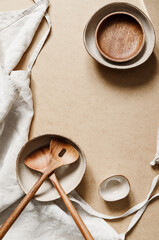 Modern minimalist ceramics set with a linen cloth over kraft paper background. Natural products or food concept, top view, flat lay.