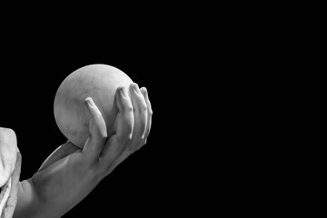 Black and white photo showing in detail the hand of a marble statue holding a stone ball