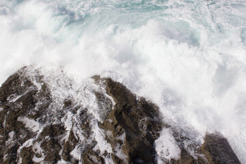 Bay of Biscay. Raging force of nature. Waves lick stones and beat against rocks. Spanish coast. Salty sea air. Boulders and stones in the spray of sea waves. Seascape view from above. Frosty breeze. 