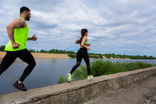 Sports guy and girl in stylish sportswear running along embankment, photo for blog or ad of sport healthy lifestyle
